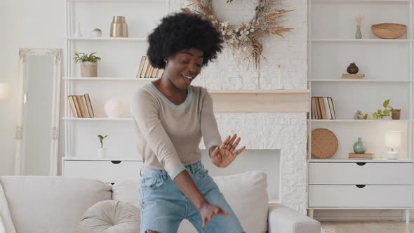 Cheerful Carefree Young African American Woman Funny Dancing Listening to Good Music at Home Alone