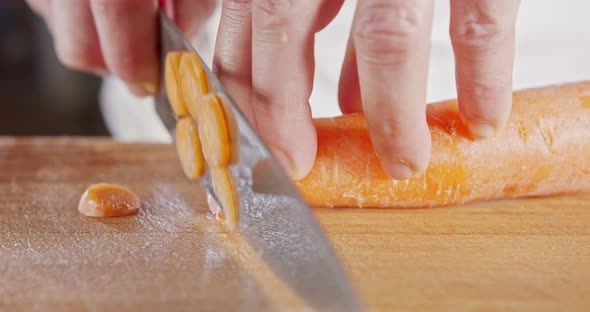 Slow motion close up of a chef knife slicing a carrot