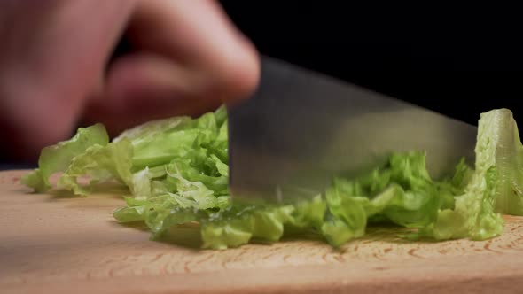 Cutting fresh lettuce leaves on a wooden cutting board 