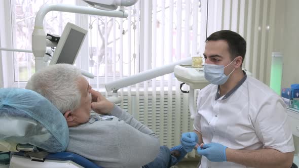 Senior Male Patient Consulting with Dentist About Removable Dentures in Dental Office