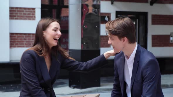 a young couple sit on a bench and smile