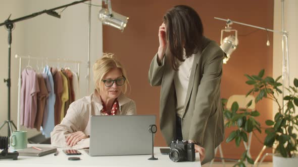 Senior Businesswoman Using Laptop and Talking with Young Colleague