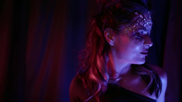 Sexy Woman is Dancing in Darkness Bright Makeup on Her Face and Shiny Crystals