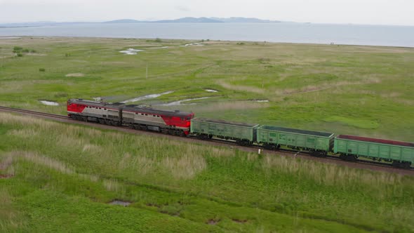 A Drone View of a Freight Train Driven By a Diesel Locomotive on a Railroad