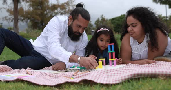 Indian parents having fun at city park playing with wood toys with their children