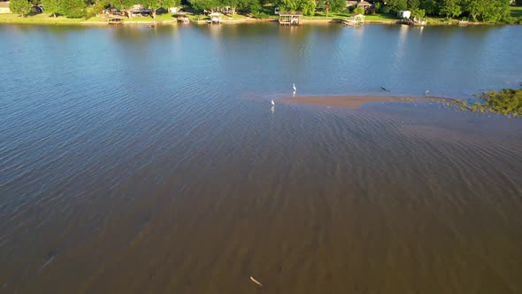 Aerial footage of Cedar Creek Lake in Texas.  Camera is flying west over a sand bar and white herons