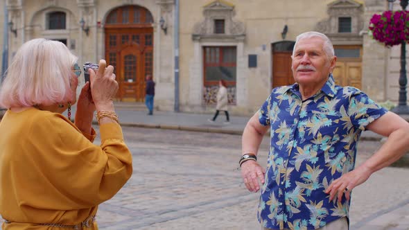 Elderly Tourist Grandfather Taking Photo Pictures of Grandmother on Retro Camera in Old Summer Town