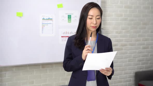 Happy Asian Businesswoman Typing on Laptop While Analysing Statistics in Office