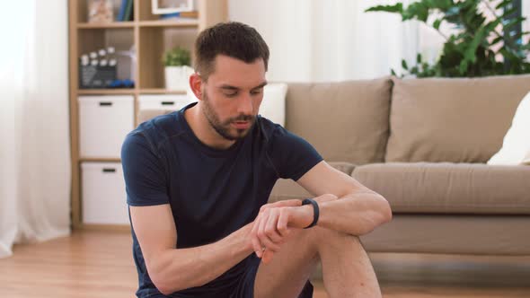 Man with Fitness Tracker Drinking Water at Home 