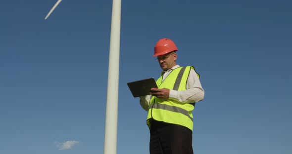 Young Male Engineer Looking at Wind Turbine Statistics Environmental Energy Energy Windmill Field