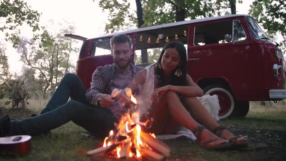 Beautiful Young Couple Roasting Marshmallows Over a Campfire While Enjoying Their Road Travel Slow