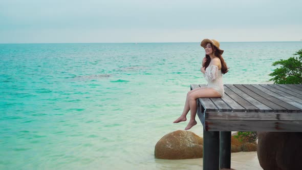 happy woman sitting on a wooden bridge in the sea beach at Koh MunNork Island, Rayong, Thailand