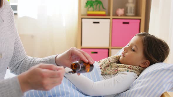 Mother Pouring Cough Syrup for Sick Daughter