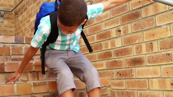 Sad schoolboy sitting alone on staircase at school