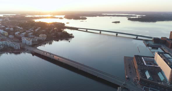 High and wide tracking shot of two bridges in Helsinki during sunset. The shot slowly tracks in reve