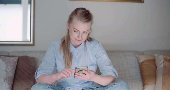 Happy Woman Browsing Smartphone At Home