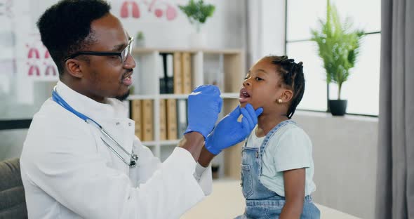African American Male Doctor which Examining Her throat and Mouth with Spatula