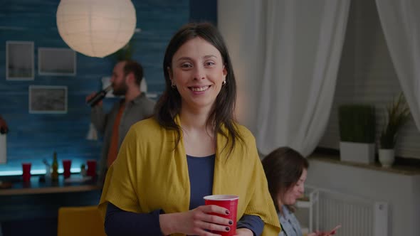 Portrait of Cheerful Woman Looking Into Camera While in Background Her Friends Having Fun