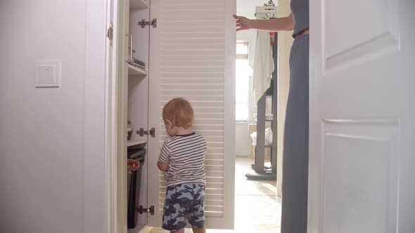A Little Baby Looks in the Open Closet and His Mom Moves Him Away to Close the Door