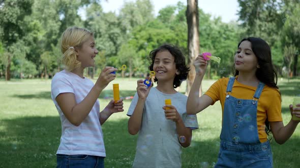 Three children are having fun, releasing soap bubbles