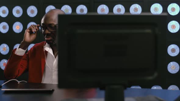 AfricanAmerican Guy Listens Music Via Phone Headset and Works on Computer