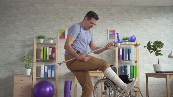 Expressive Man with a Bandaged Leg Dancing with Crutches at the Rehabilitation Center