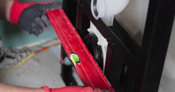 A Worker Applying a Spirit Level Tool to a Plastic Pipe to Check the Correctness of the Technology