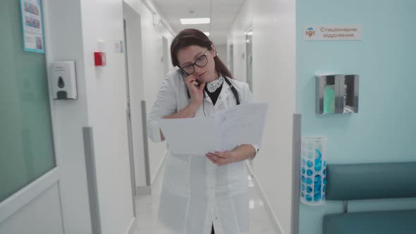 Medical Doctor of Hospital Looking Through Medical Records While Walking Along Corridor of Modern