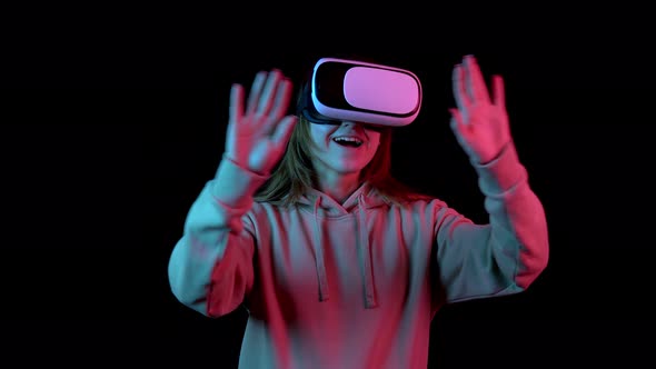 Young Woman in VR Glasses. A Woman Immersed in Virtual Reality Makes Movements with Her Hands. Blue