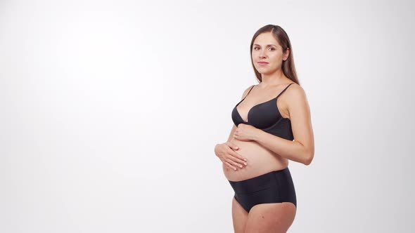 Young, happy and healthy pregnant woman in front of white background.