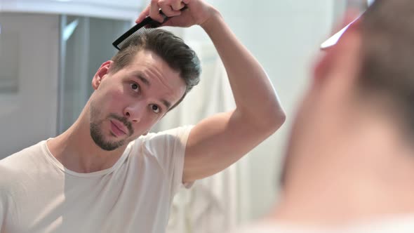 Young Man Combing Hair in Mirror