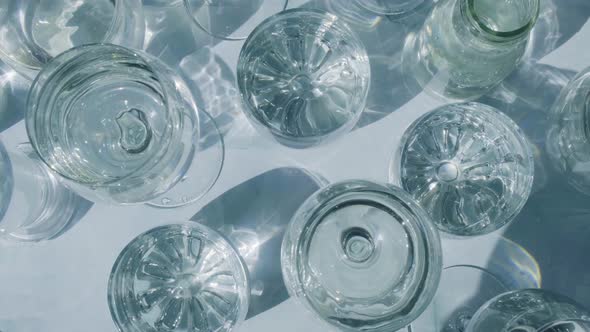 Beautiful Different Glasses Stand on White Background in Sunlight and Create Shadows