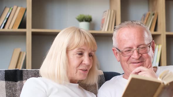 Happy Old Married Couple Reading Book Together in Home Library