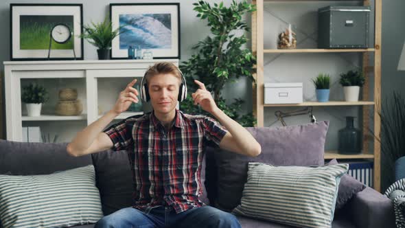 Zoom-in of Happy Guy Melomaniac Putting on Headphones and Listening To Music and Smiling Enjoying