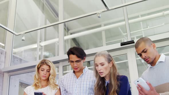 Colleagues discussing over laptop while using mobile phone 4k