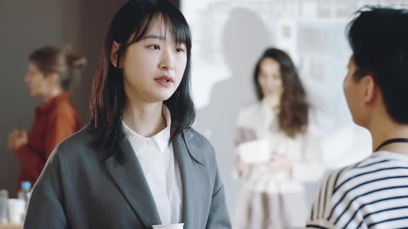 Asian Woman Speaking with Female Colleague on Business Event