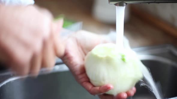 Woman washing fennel bulb under running water