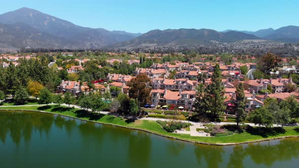Aerial drone rising over community lake and condos with mountains as background