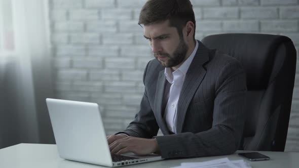 Agitated Businessman Nervously Typing on Laptop, Worrying About Startup Success