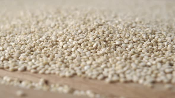 Raw quinoa falls in slow motion onto a wooden cutting board