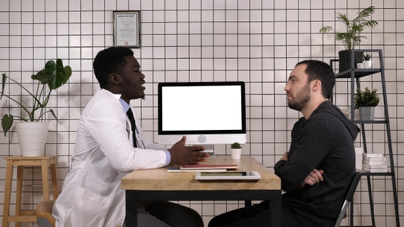 Doctor showing medical records on his computer to his patient