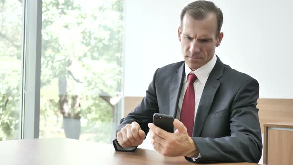 Businessman Upset for Loss While Using Smartphone