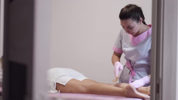 Specialist Doing Waxing Hair Removal Procedure in Salon