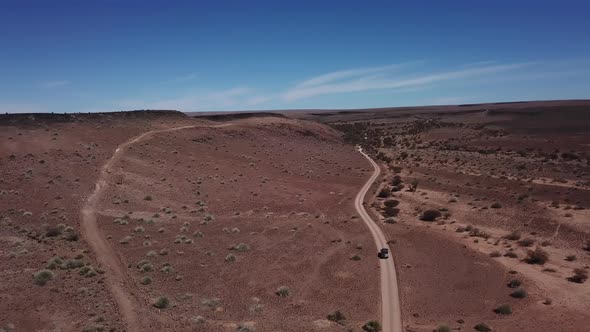 Car Driving on Gravel Road in Aerial Desert