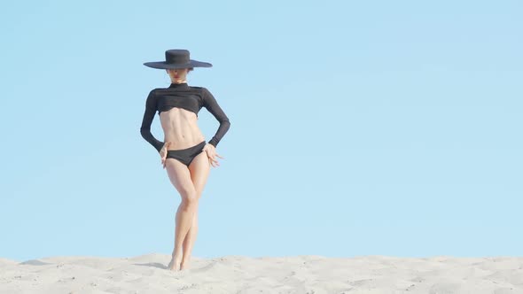 Stunning Elegant Woman in Big Black Hat Dancing on Sand