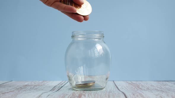 Putting bitcoin coin cryptocurrency in glass jar.