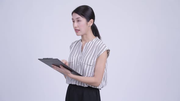 Beautiful Asian Businesswoman Directing While Reading on Clipboard