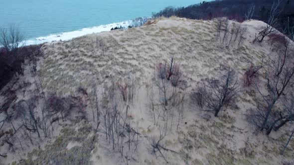4K drone video of a sand dune revealing Lake Michigan inn the winter