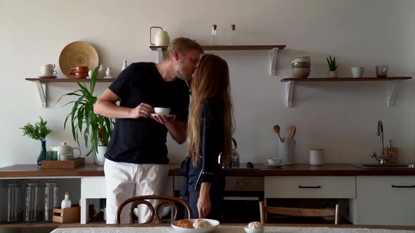 Young Woman Is Kissing Her Husband on Kitchen at Sunday Morning, Breakfast Time