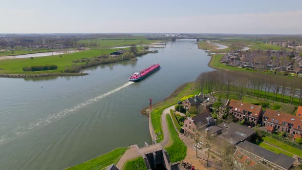 Aerial view of red boat sailing down river in Dutch countryside